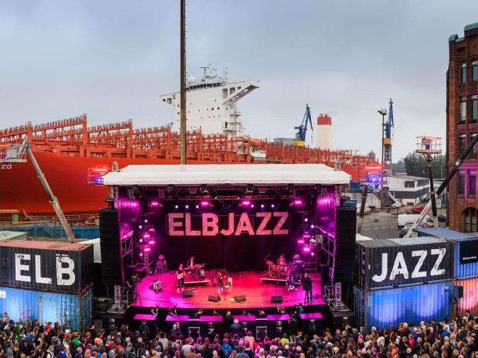 Eine Festivalbühne vor einem großen Containerschiff