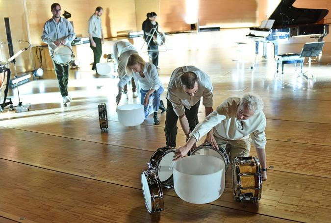 Musikerinnen und Musiker spielen auf Trommeln und Schüsseln