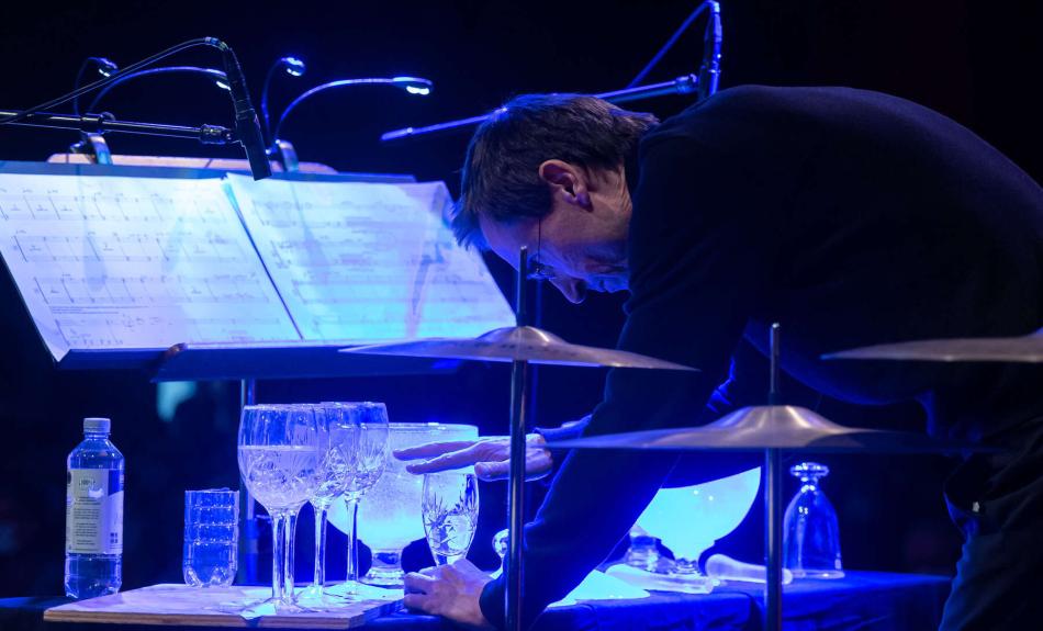 Mann erzeugt Klänge mittels mit Wasser gefüllten Gläsern