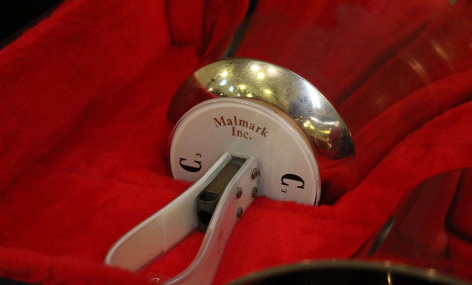 Glocke des Handglockenchors Bad Schandau. Das Instrument liegt in einem mit rotem Sand audgekleideten Glockenkasten.