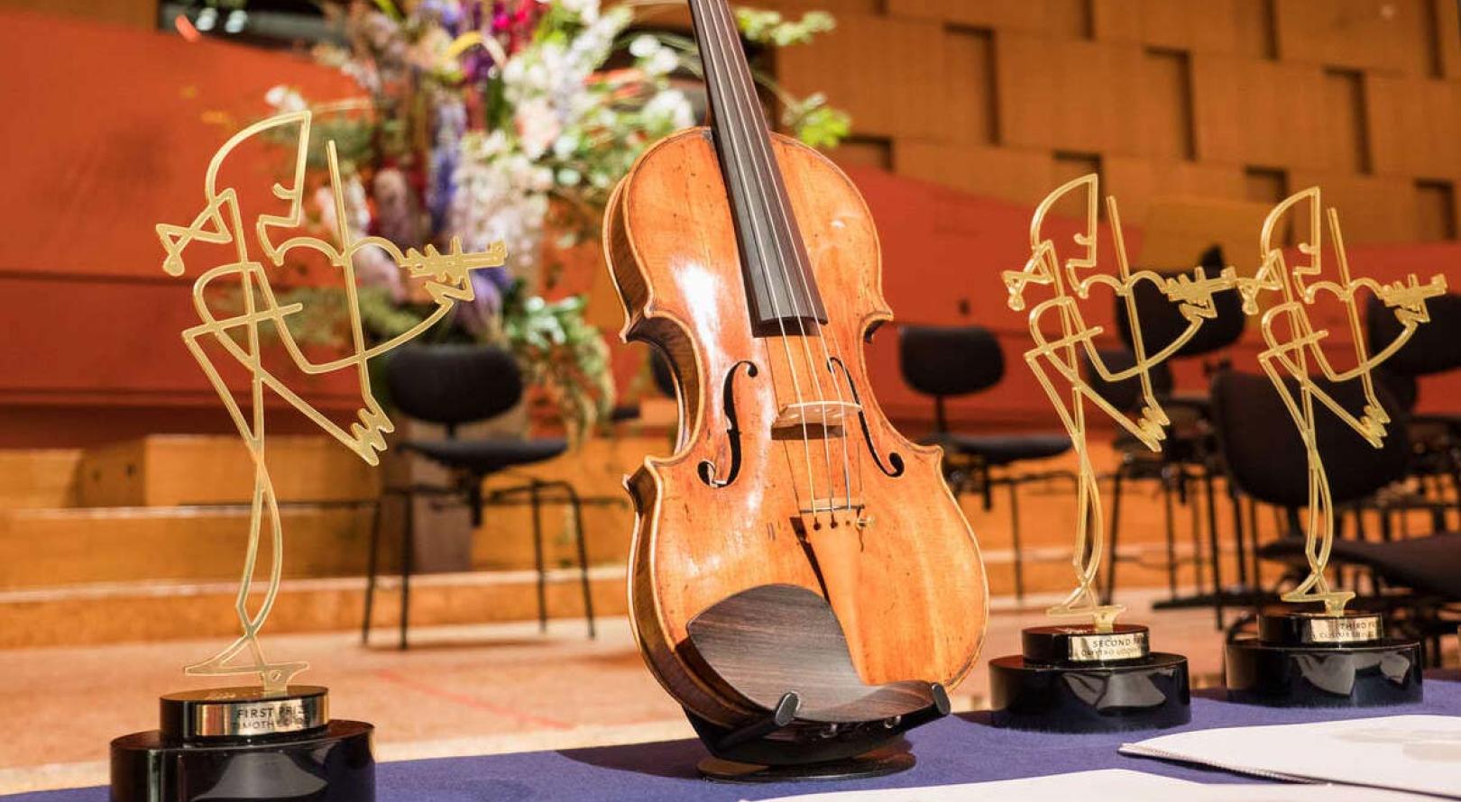 Eine Violine zwischen den Trophäen für den Joseph Joachim Violinwettbewerb 2018.