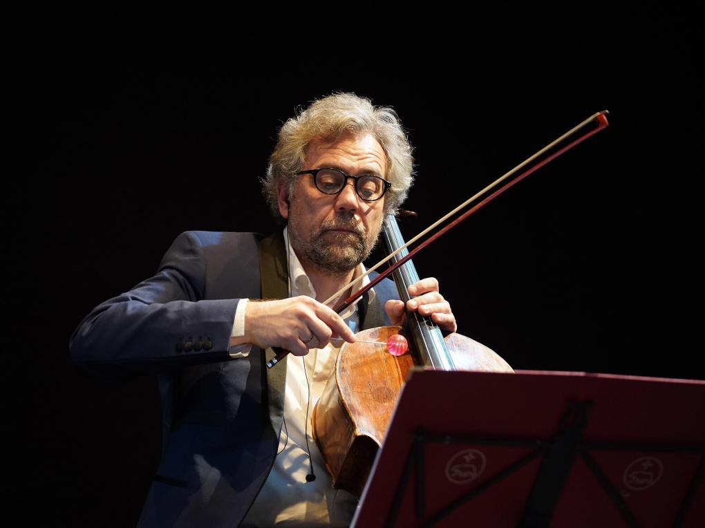 Cellist klopft mit Lutscher gegen sein Musikinstrument