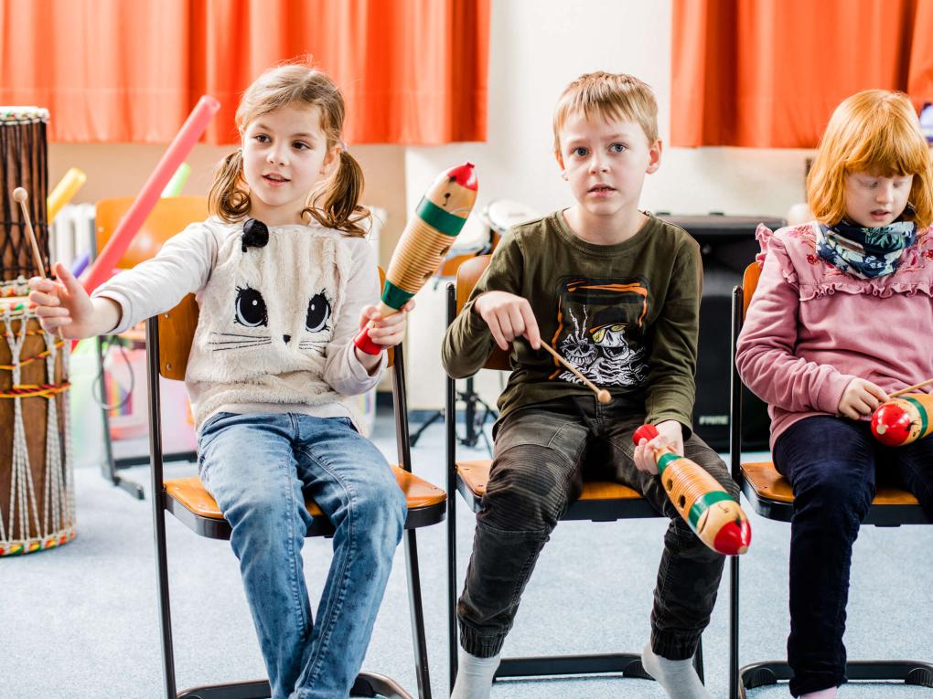 Drei Kinder spielen auf Güiros