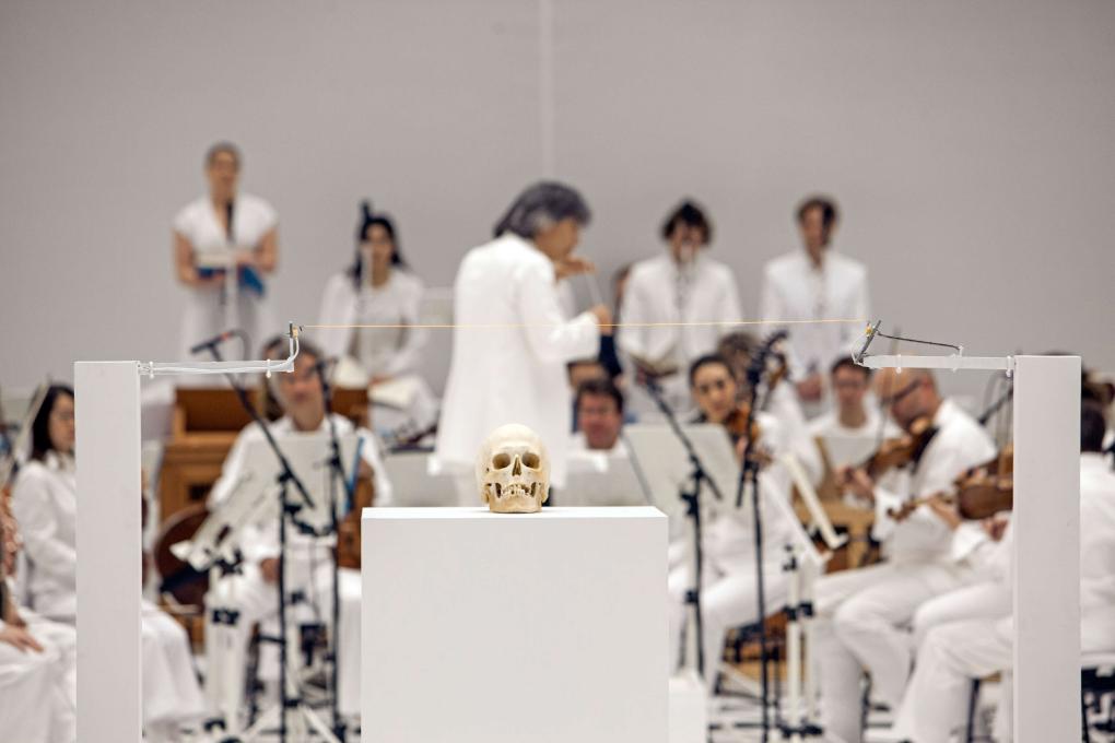 Bei der Inszenierung von "La Passione" an der Staatsoper Hamburg sind alle Beteiligten auf der Bühne ganz in weiß gekleidet. Im Vordergrund ist ein Schädel positioniert.