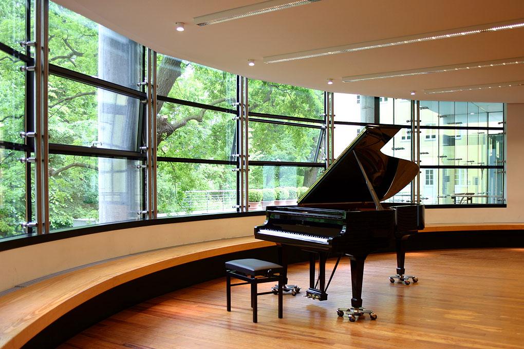 Raum mit Parkett und großer Fensterfront, in der Mitte ein Konzertflügel