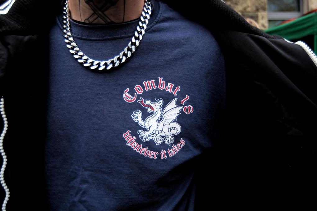 Mann mit T-Shirt mit der Aufschrift „Whatever it takes“, dem Logo und Motto der extrem rechten Struktur „Combat 18“