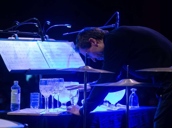 Mann erzeugt Klänge mittels mit Wasser gefüllten Gläsern